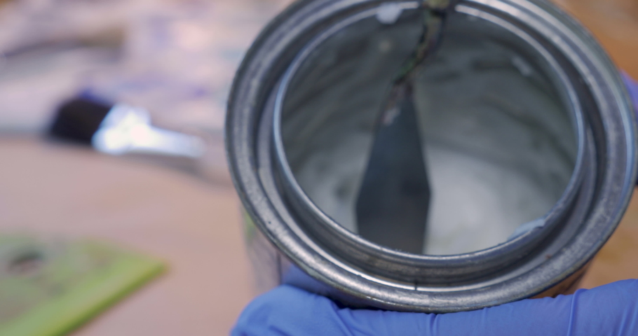 Artist scooping out paste or cold wax from a small can with a palette knife