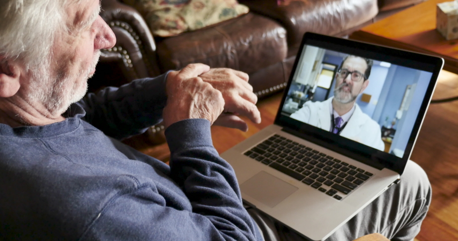 Senior man following the advice of his doctor during a telemedicine appointment while moving his wrist around to evaluate an illness or injury Royalty-Free Stock Footage #1044815029