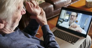Senior man having a virtual exam during a telemedicine appointment with his male doctor, or physicians assistant and getting medical advice about his wrist