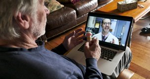 Senior man using a laptop computer for a telemedicine appointment with his doctor and getting information about his prescription medication and drugs in his home