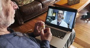 Aging senior getting medical information from his health care provider, doctor, or nurse over a video chat on his laptop computer via a telemedicine session