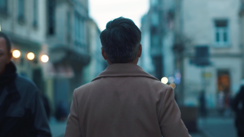 Back view of unrecognizable man walks along the city center street looks around city lights on background business downtown evening happy close up slow motion  | Shutterstock HD Video #1044817249