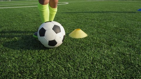 Close-up of feets in soccer shoes skillfully dribbling and kicking balls during training on football field with artificial grass. Member's of soccer team developing football skills on sports ground
