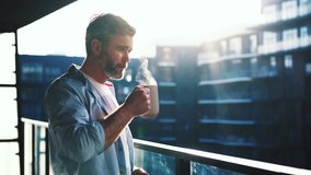 Dreaming european middle aged man stands in the balcony with great views and drinks hot coffee or tea, sun shine, enjoying beautiful morning feeling happy slow motion - Powered by Shutterstock - Get 15% off with code: PIKWIZARD15