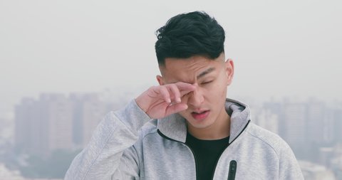 slow motion of asian man has allergy and has itchy eyes standing in the city