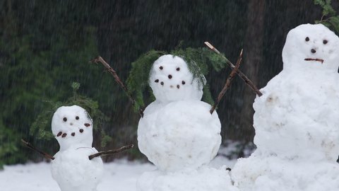 Snowman Family Parents and Children Midshot Panning Across Faces Winter Snow Falling in Pine Tree Forest