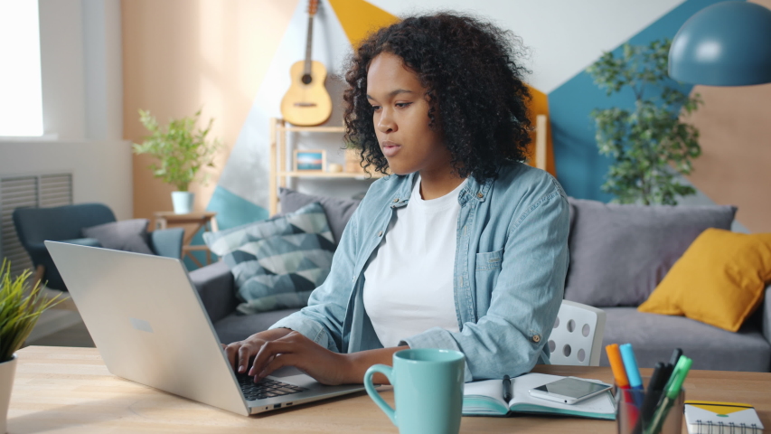 Excited young African American business lady is enjoying success at freelance work at home looking at laptop screen having fun celebrating good news. | Shutterstock HD Video #1044832963