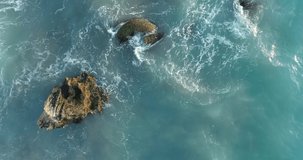 Aerial view of crashing waves on rocks. Storm in the mediterranean sea. Top view of ocean blue waves crashing coastline cliff drone footage. 4K