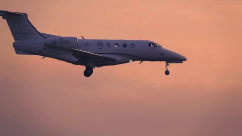 Business jet (private jet) landing at sunset. Side view