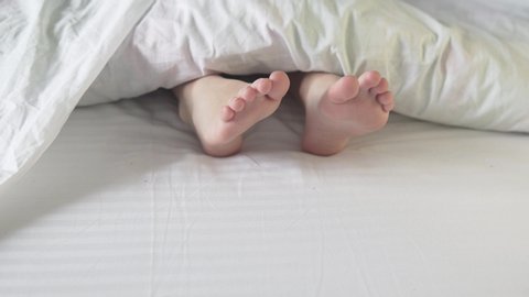 Boy legs in bed view from above, white bedding