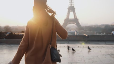 Rear view happy tourist woman running to misty sunrise Eiffel Tower view in Paris on romantic vacation trip slow motion.