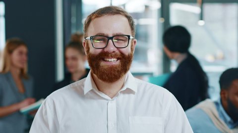 Portrait young man team leader with smiling face posing in office confident business executive ceo looking at camera startup founder training work startup success successful beard close up slow motion