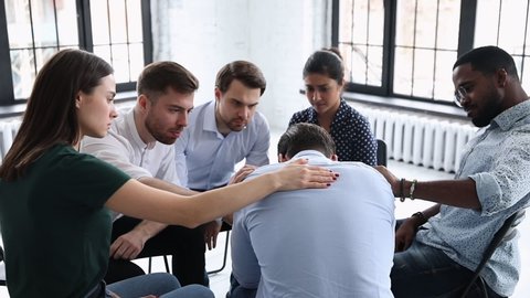 Upset man get psychological support from diverse friends counselor helping at group therapy, male patient feel pain depression share problem addiction during counseling meeting rehab session concept