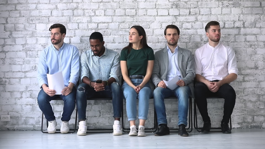 Stressed diverse ethnicity business people applicants waiting for their turn preparing for job interview sit in line queue on chairs, human resources and recruitment, rivalry in job search concept Royalty-Free Stock Footage #1044846397
