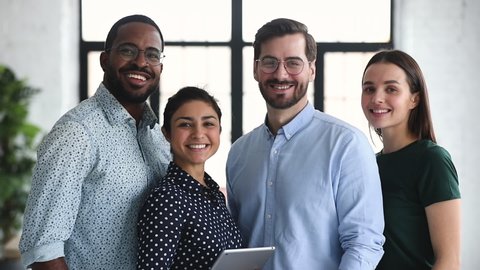 Smiling professional diverse corporate office business team members group look at camera, four happy proud confident multiracial leaders employees staff diverse people group stand together, portrait