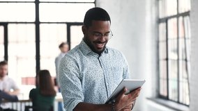 Young professional african businessman worker using digital tablet corporate software standing in office, smiling ethnic male manager working online on pad computer tech in modern company office - Powered by Shutterstock - Get 15% off with code: PIKWIZARD15