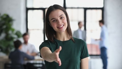 Confident friendly happy young female business professional hr representative consultant manager looking at camera extending hand for handshake introducing or greeting client concept, portrait