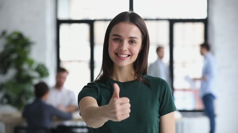 Happy proud confident young professional business woman leader winner employee looking at camera showing thumbs up hand sign gesture in office recommend best job choice concept, closeup portrait