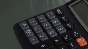 4K close up video of accountant hand using a classic financial calculator and pressing keys to compute numbers. Classic calculator with grey keys and black colour. Investment or investing concept