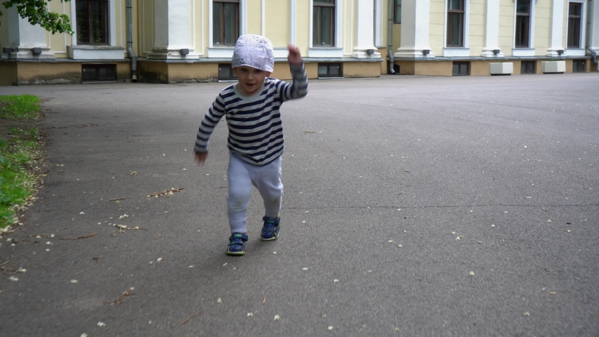 Active toddler boy running on asphalt road in park. Stabilizer Gimbal movement motion shot