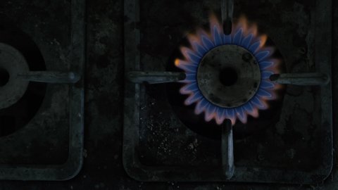 Kitchen burner turning on. Old dirty Stove side burner igniting into a blue cooking flame. Natural gas inflammation, close up.