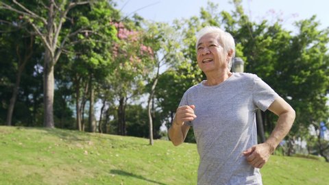 happy asian old man jogging outdoors in a park
