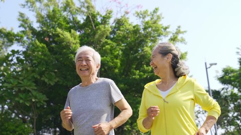 happy senior asian couple jogging outdoors in a park