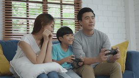 Happy family mother cheer son playing video game won father on sofa at home