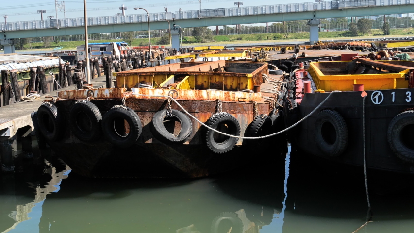 Two vessels on the harbor port in the city with the hanging tires on the side of each vessel