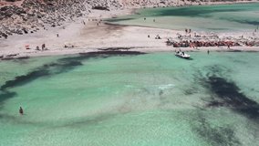 Aerial static video view from  drone on Balos lagoon with sandy sea beach with sunbathing and swimming tourists. Dimos Kissamou, Chania prefecture, Crete, Greece.