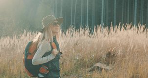 Woman hiking backpacker traveler camper walking on the top of mountain in sunny day under sun light. Beautiful mountain landscape view. 4K slow motion video
