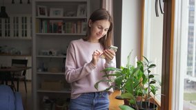 Close up young woman stands near the window at home use phone communication female message cellphone cheerful smile internet modern smartphone portrait. Texting browsing social media. 4k - Powered by Shutterstock - Get 15% off with code: PIKWIZARD15