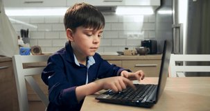 A boy blogger works at a computer. The text of the child surf on the Internet is typed. Prohibited sites, naive child on the Internet