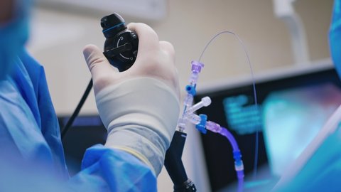 Endoscopic surgery. Surgeon's hand holds medical instrument on the blur background of a monitor. Close-up.