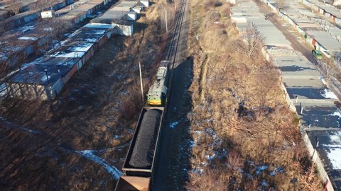 Freight train moving in winter. Top view on a cargo train on rails. Freight transport, railroad and transportation concept. Aerial view.