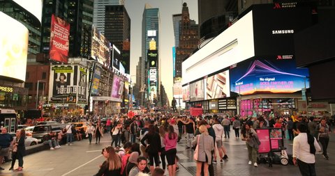 Manhattan, New York - September 18, 2019: People gather by the digital advertising and brightly lit billboards at night on Broadway in Times Square New York City USA