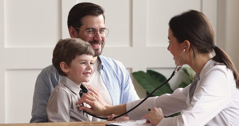 Female doctor pediatrician using stethoscope listen heart of happy healthy cute preschool kid boy give high five to child patient at medical visit with dad in hospital, children healthcare concept