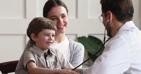 Smiling healthy cute trusting child boy patient giving high five to male professional doctor pediatrician checking up kid health heartbeat with stethoscope during pediatric visit with parent mom