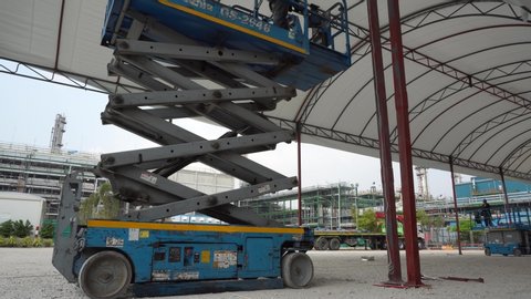 January 2020 in Rayong city Thailand. Workers are use control panel to drive the blue scissor lift or hydraulic mobile portable automotive machine to go up and down the work at high.