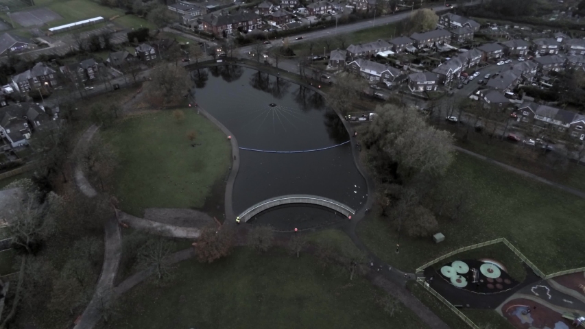 Aerial view above park, Illuminated lake attraction light show at night. High orbit right dolly.