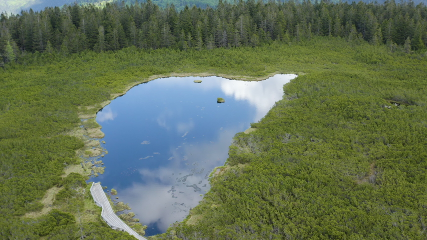 Aerial circling shot around remote lake Ribnica in slovenia with amazing sky reflection from the lake