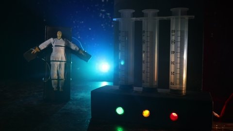 Lethal injection concept. Prisoner handcuffed to death by lethal injection. Creative artwork decoration with scale model on dark with lights.
