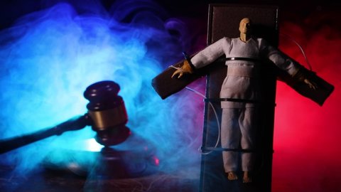 Lethal injection concept. Prisoner handcuffed to death by lethal injection. Creative artwork decoration with scale model on dark with lights.
