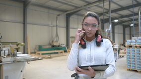 Young woman apprentice working in woodwork warehouse