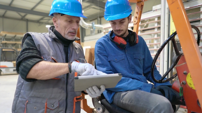 Man giving instructions to apprentice in warehouse, using cart Royalty-Free Stock Footage #1044929497