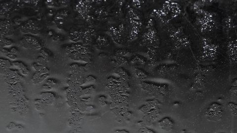 rain falls heavily on the window forming small drops that slide on the glass