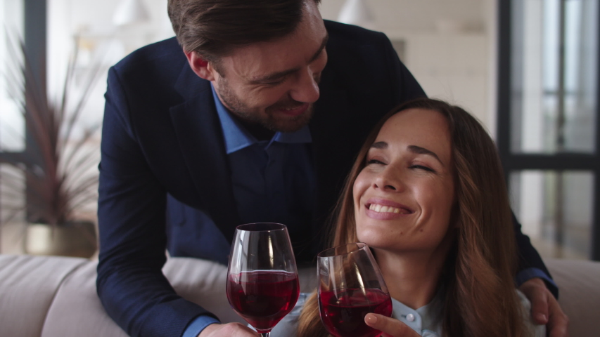 Closeup romantic couple celebrating success with wine at home. Successful family drinking alcohol at living room. Handsome man bringing glasses of wine to wife in slow motion. Royalty-Free Stock Footage #1044935341