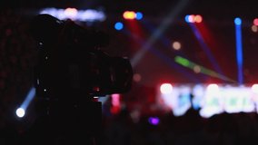 Slow motion,silhouettes of people partying, Videographer is recording video rock concert in front of stage in big hall. Colorful blue stage lighting,Stage Spotlight with Led light.entertainment concept