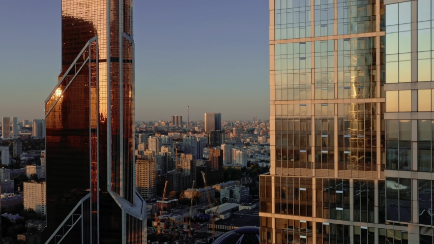Aerial drone zoom out flying over center of Moscow city buildings, skyscrapers during sunset. Drone shot flying over Moscow skyscrapers in summer evening