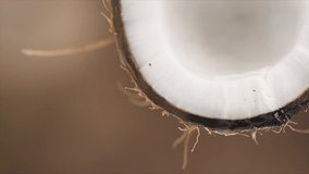 Coconut pouring water, dripping coconut milk, drops of coco nuts oil over brown background. Tropical Coco nut closeup. Healthy Food, skin care concept. Vegan food. 4K UHD video, slow motion